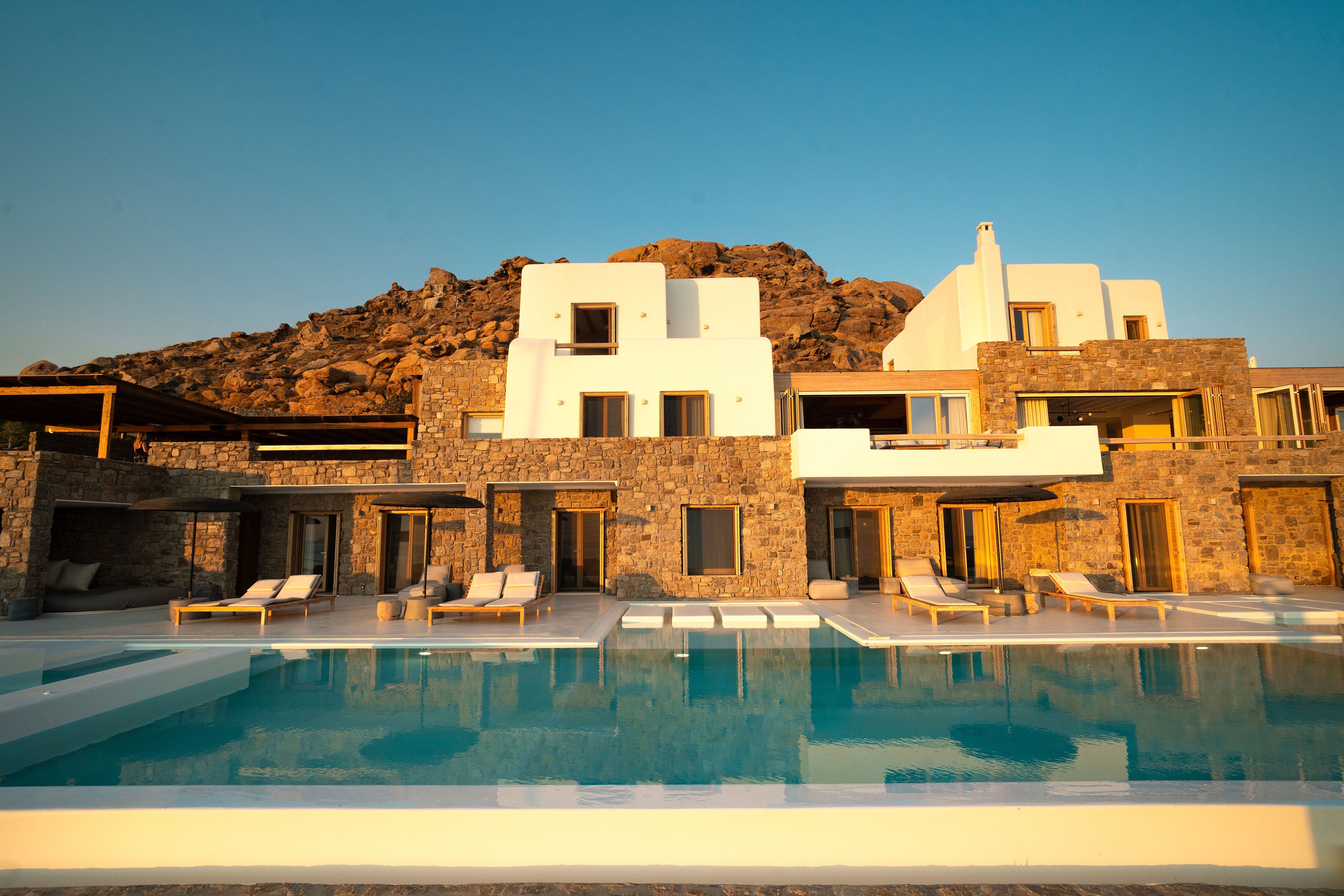 Luxury villa with pool and chairs against a mountainous background