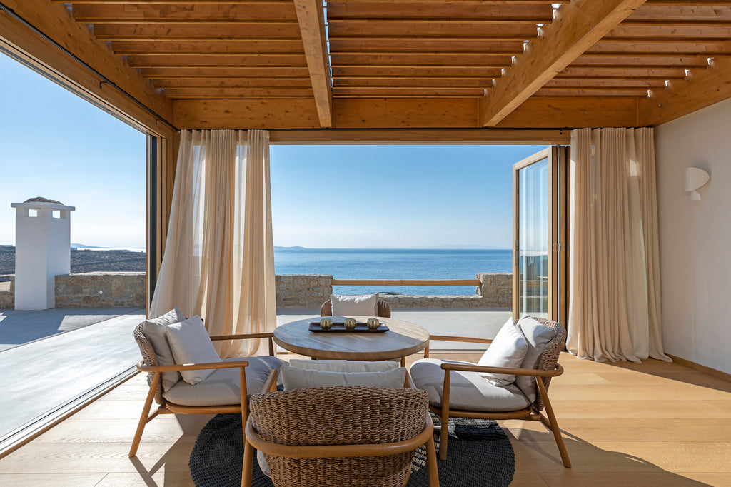 Outdoor patio with wooden chairs, table, and ocean view