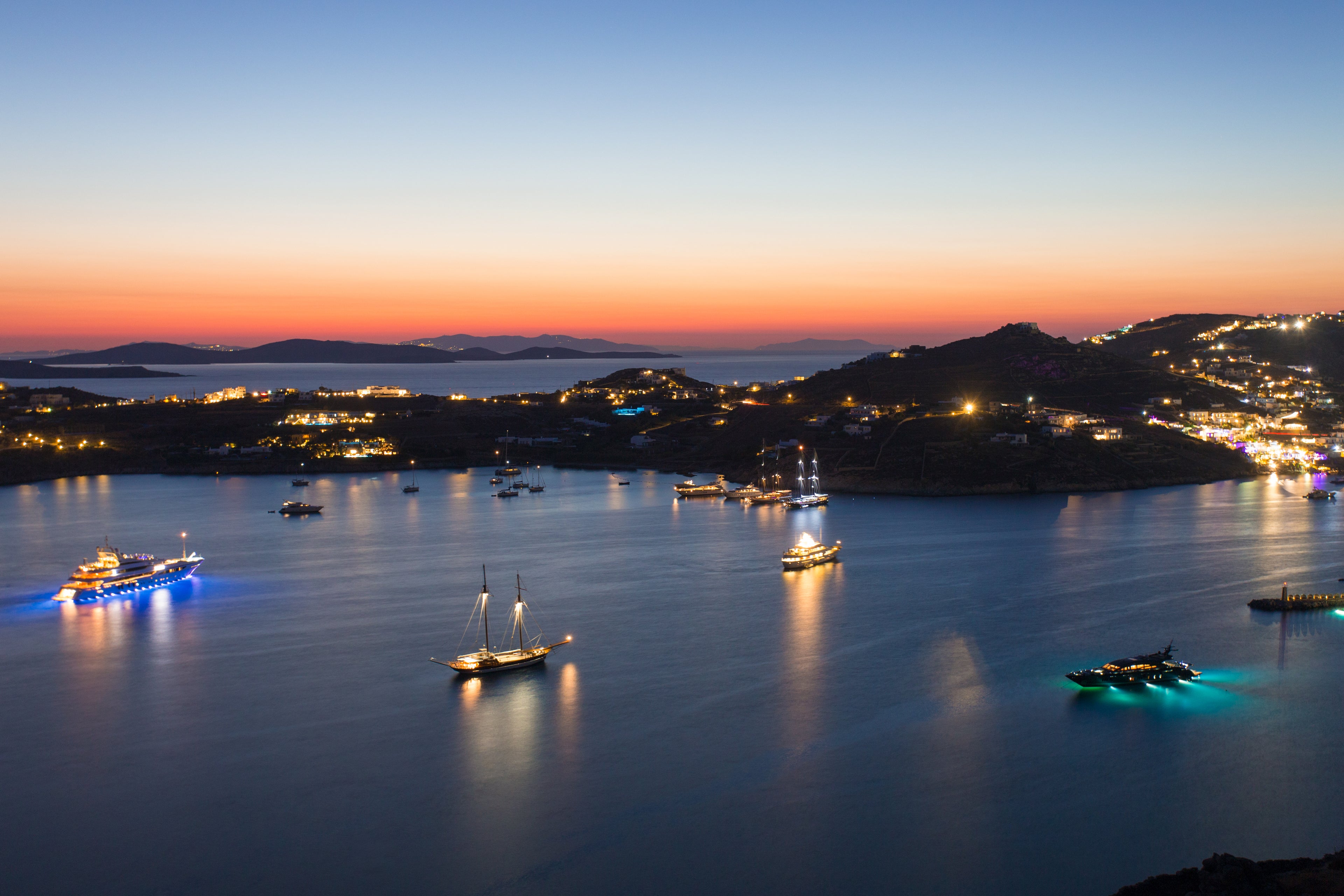 Evening view of a coastal town with illuminated boats on the water.