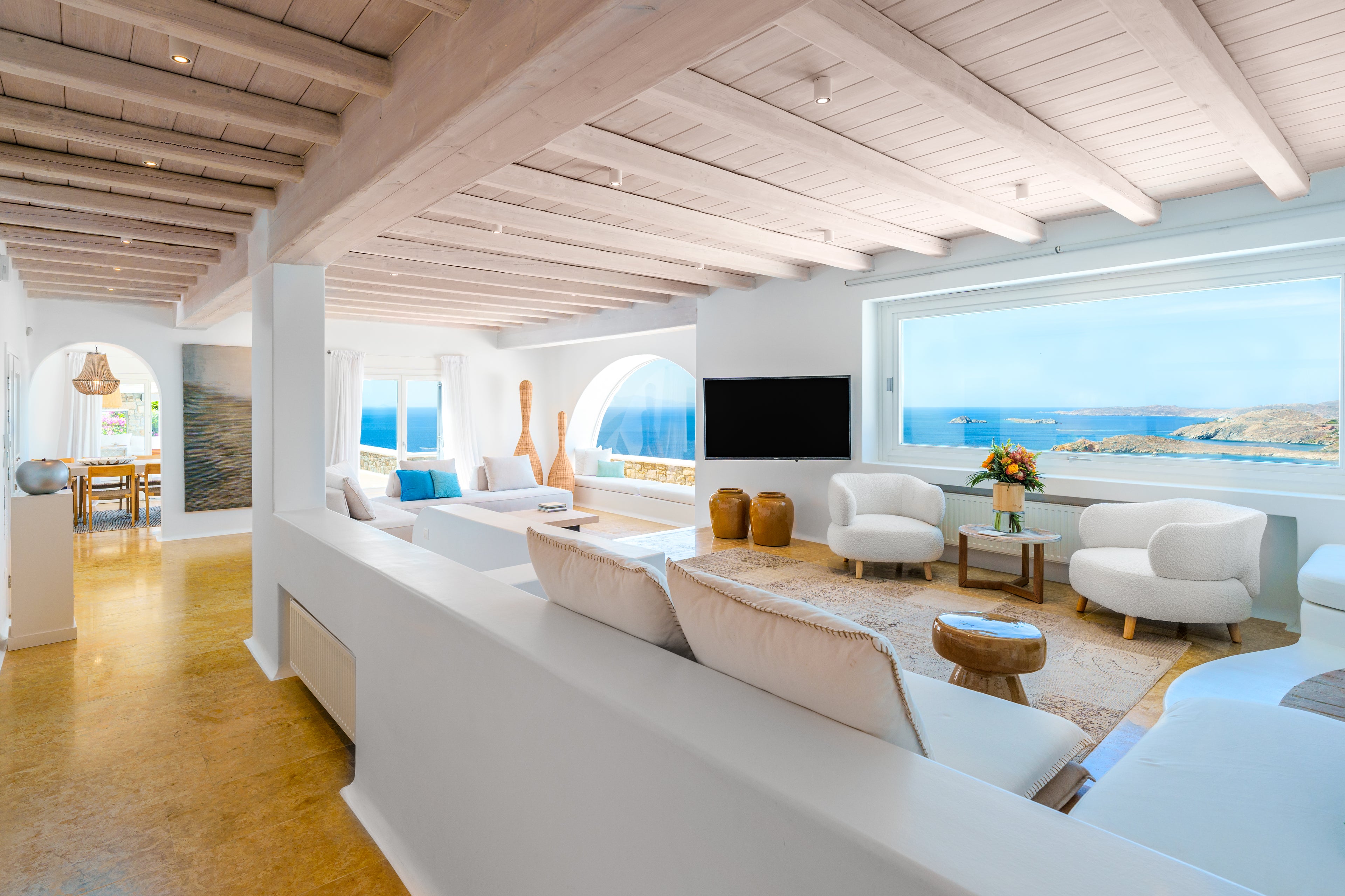 Modern living room with white furniture and a large window view of the ocean.
