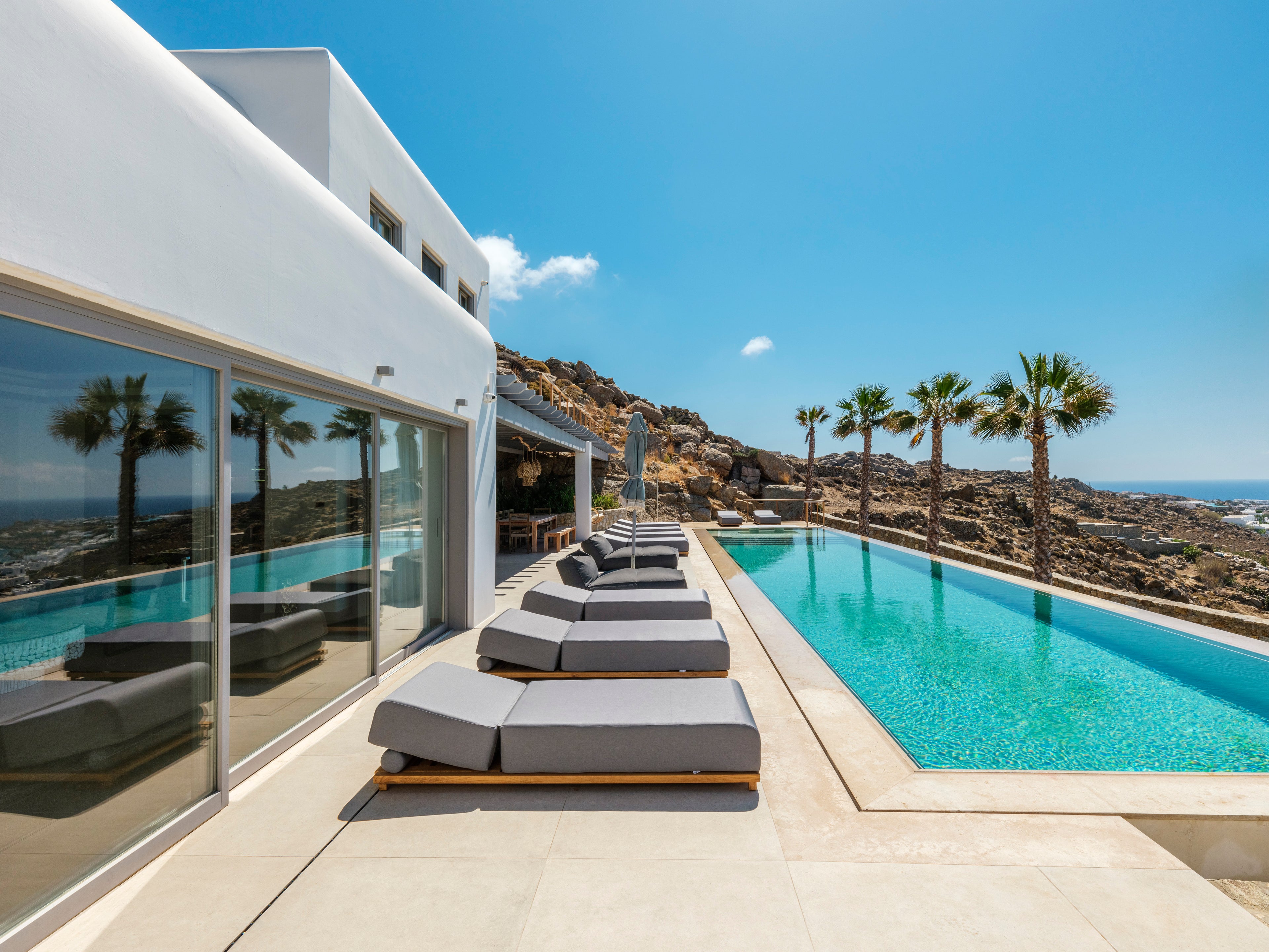 Modern outdoor area with lounge chairs by a pool and ocean view