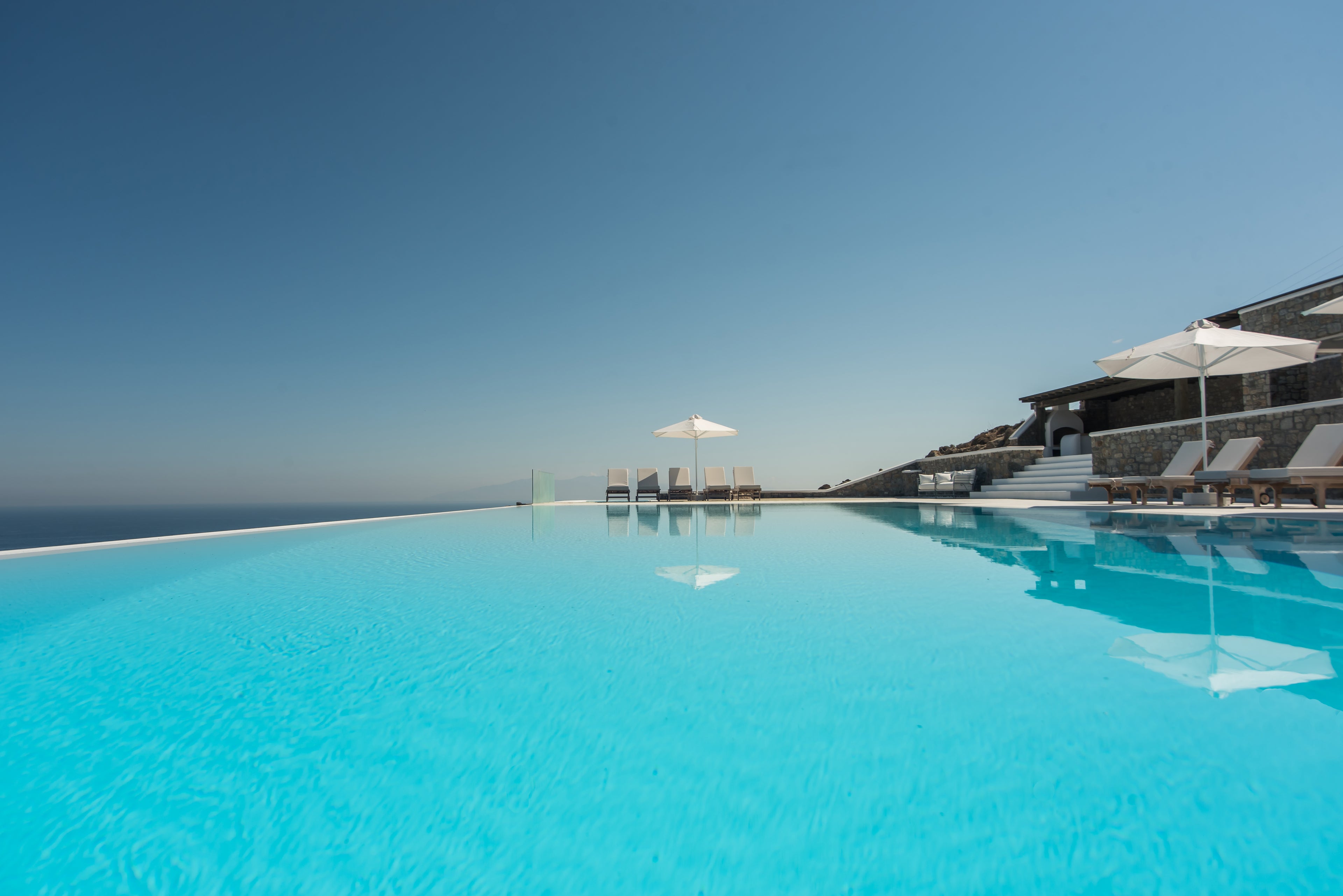 Infinity pool with ocean view and modern building in the background