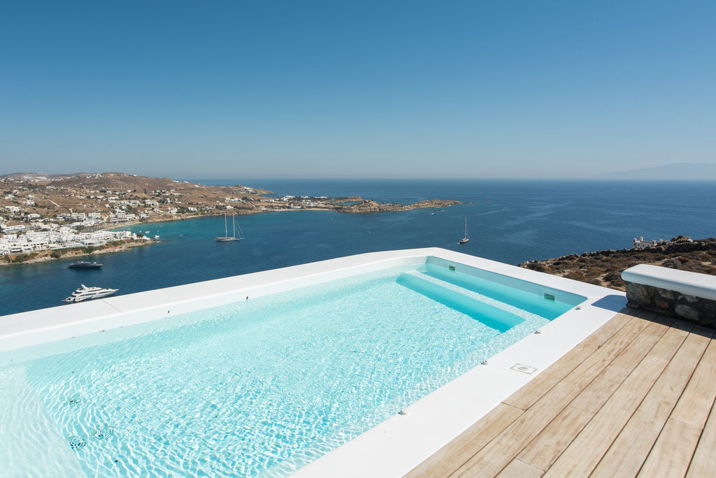 Infinity pool with a scenic view of the ocean and coastal town.