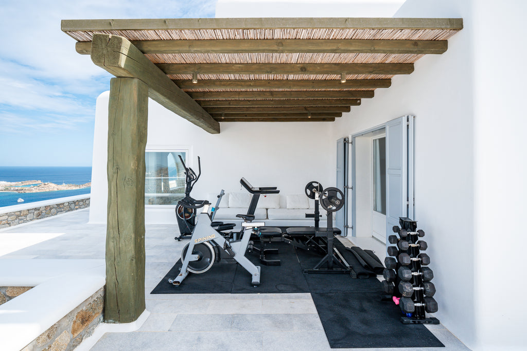 Outdoor gym area with exercise equipment on a patio overlooking the ocean.