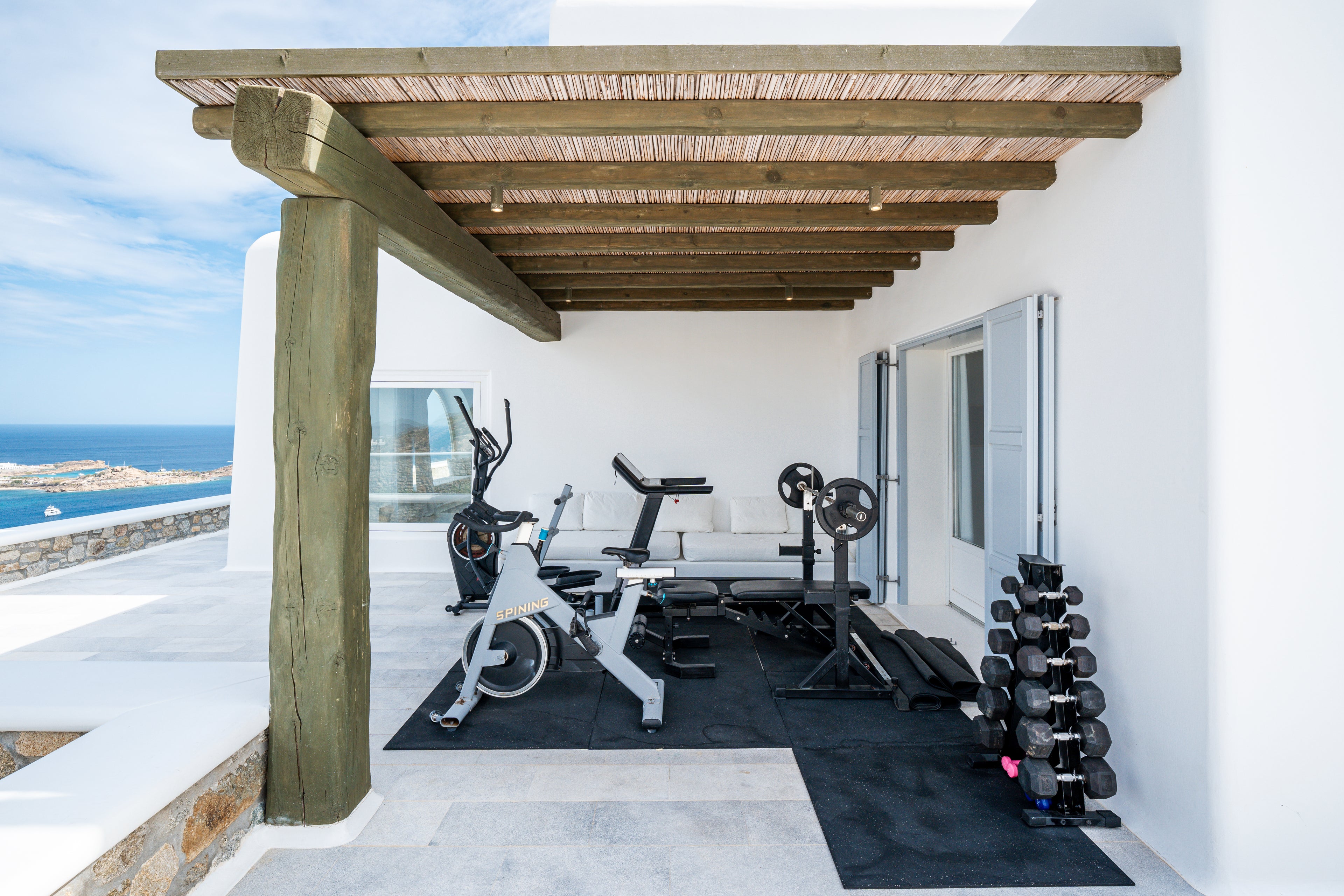 Outdoor gym area with exercise equipment on a patio overlooking the ocean.