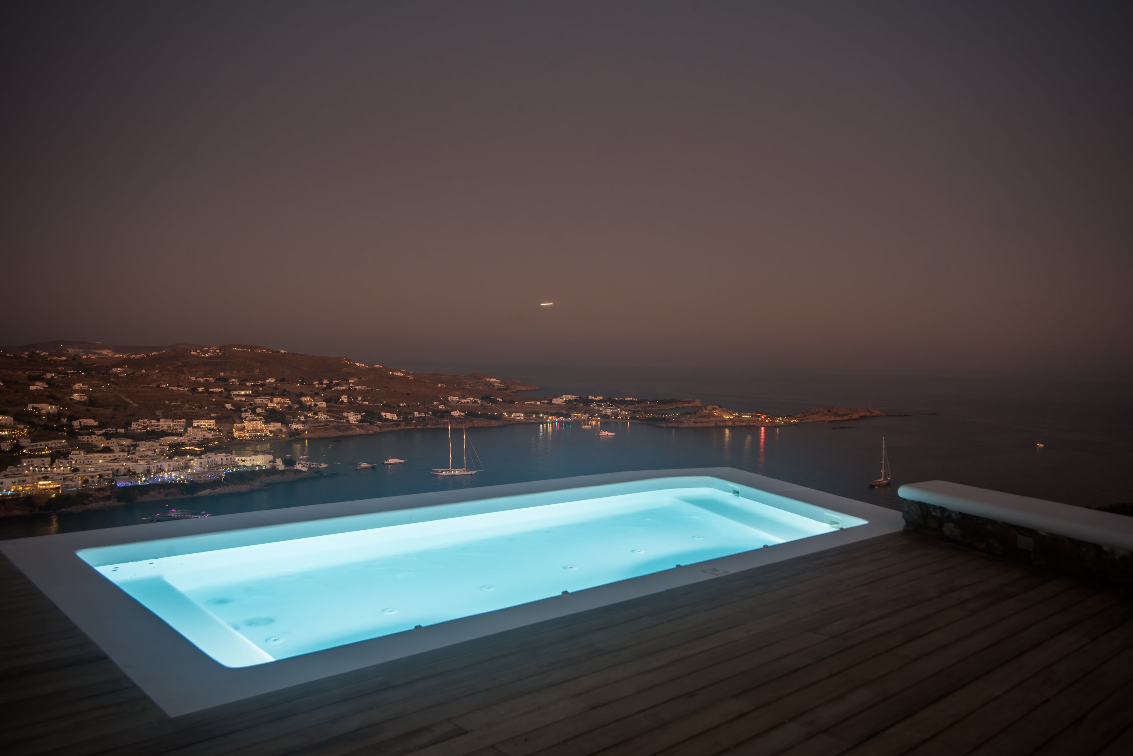 Pool with a view of a coastal town at night