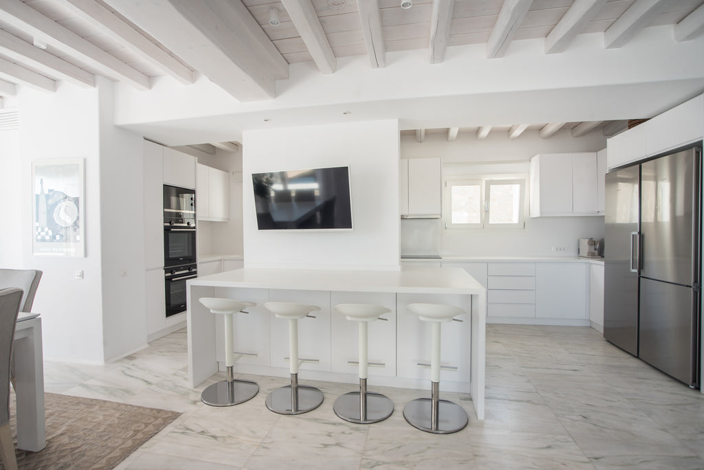 Modern kitchen with white island, stools, and stainless steel appliances.