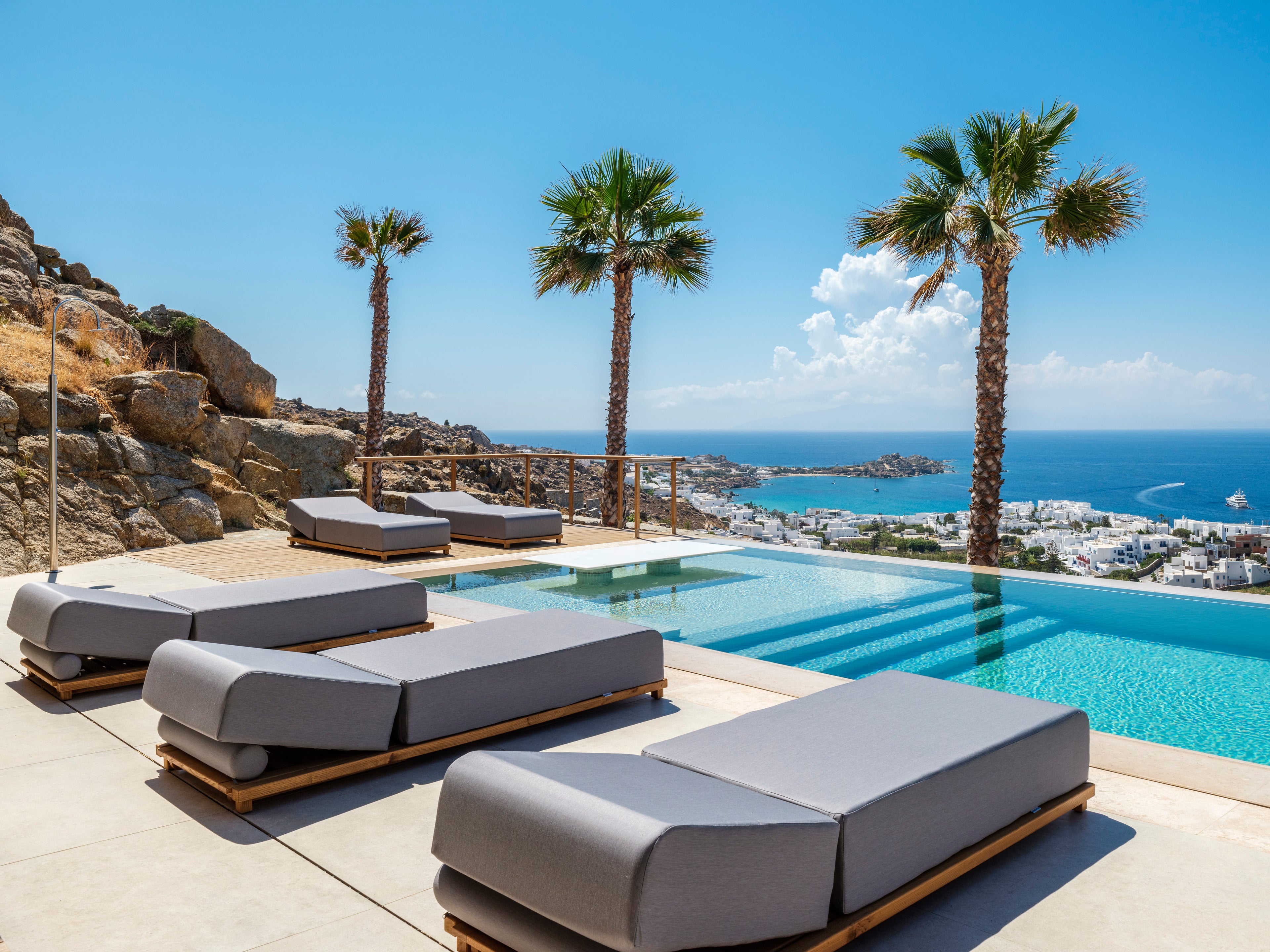 Outdoor lounge chairs by a pool with a scenic ocean view.