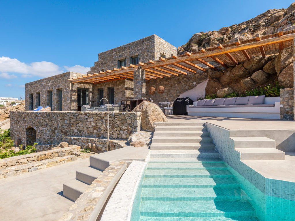 Luxury villa with stone exterior, wooden pergola, and pool area.