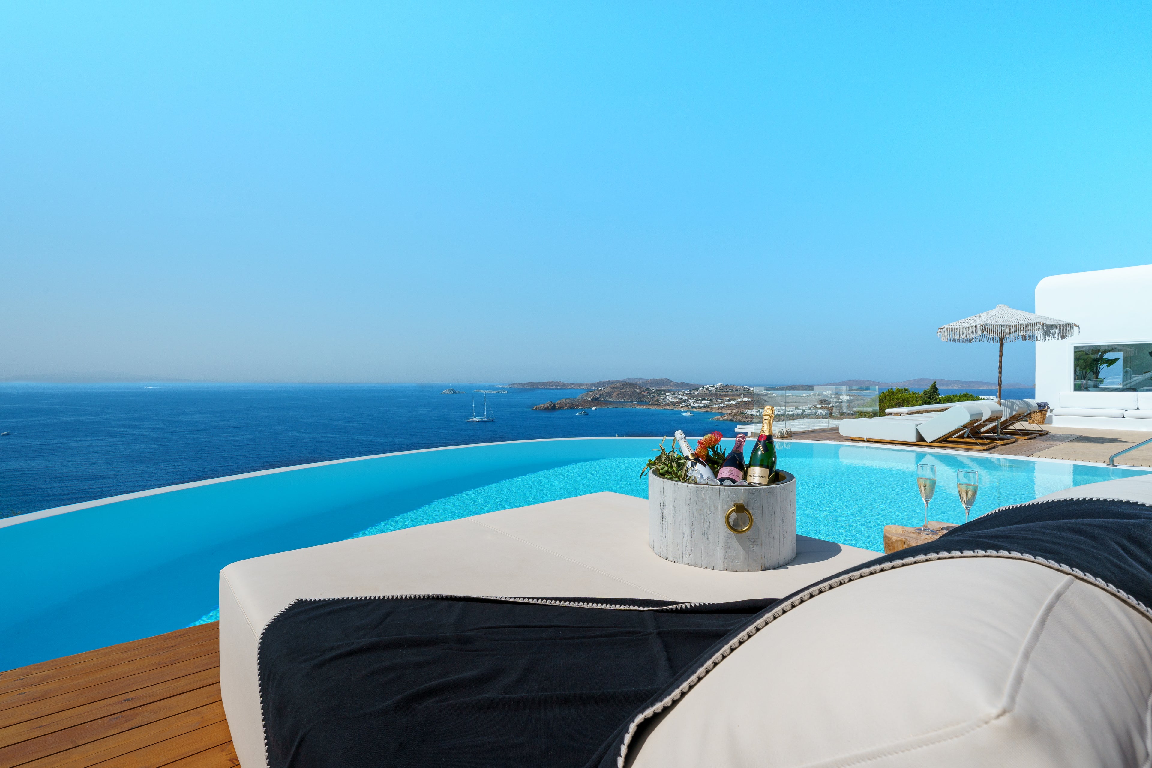Infinity pool with ocean view, lounge chairs, and a table with drinks.