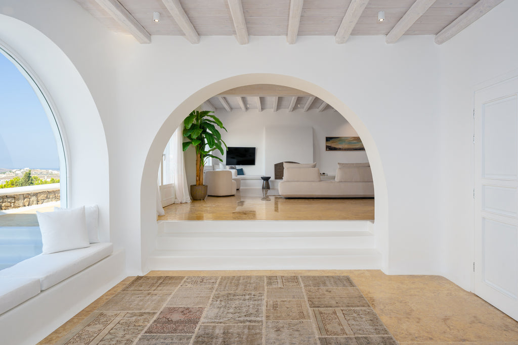 Modern living room with white walls, wooden floor, and a large window.
