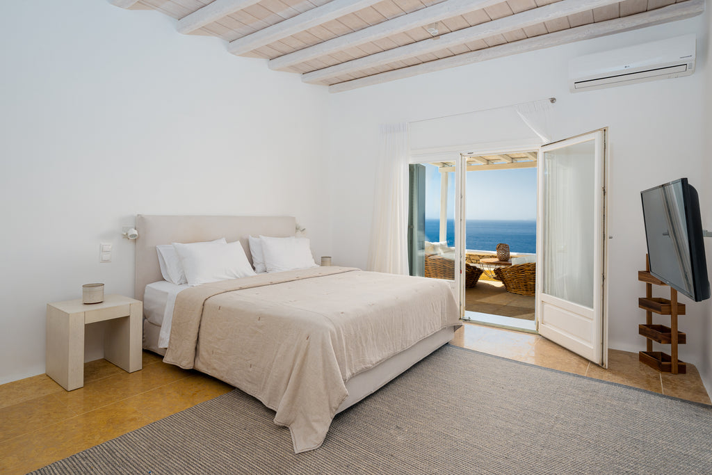 Modern bedroom with a bed, nightstands, and a television, featuring a scenic view.