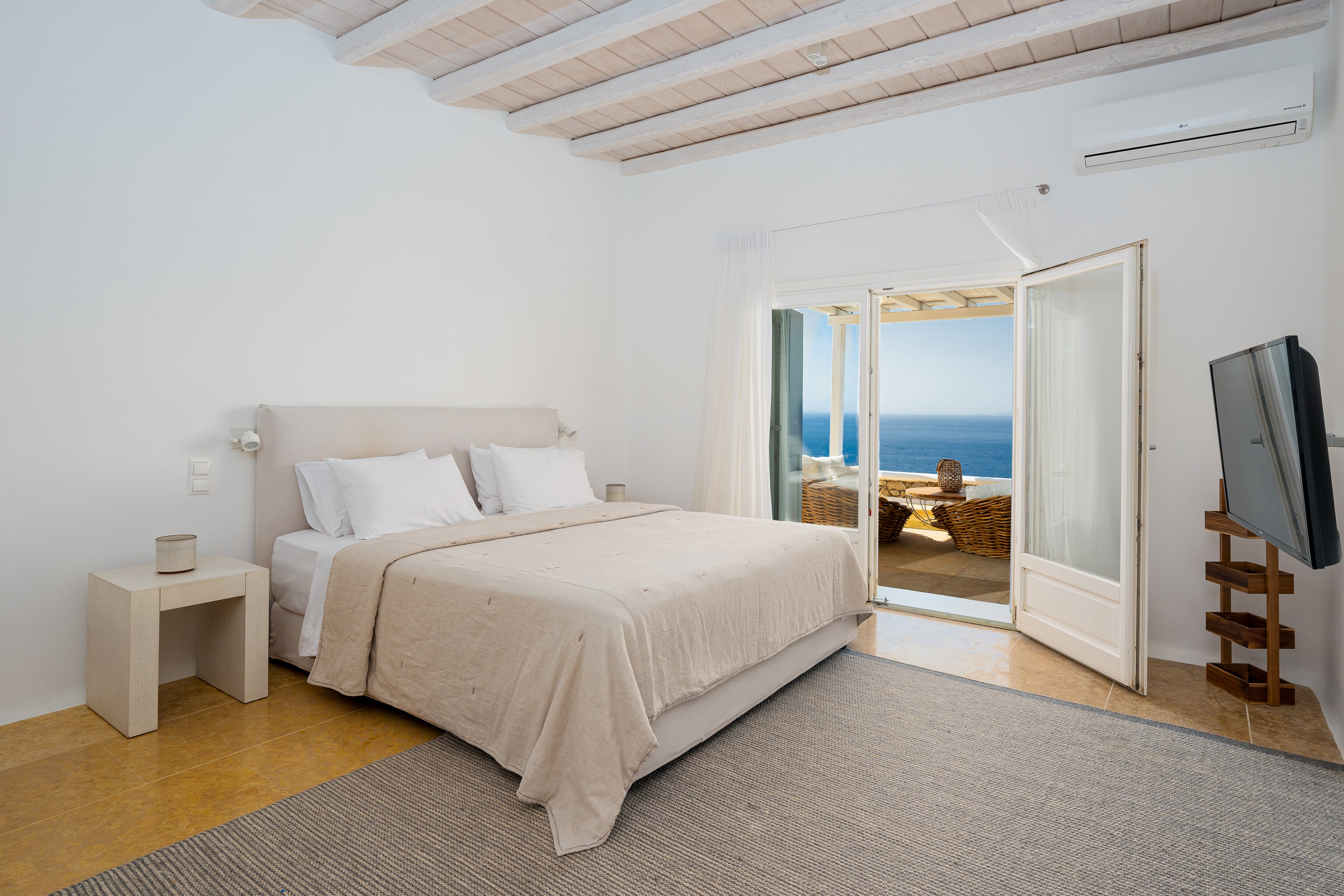 Modern bedroom with a bed, nightstands, and a television, featuring a scenic view.