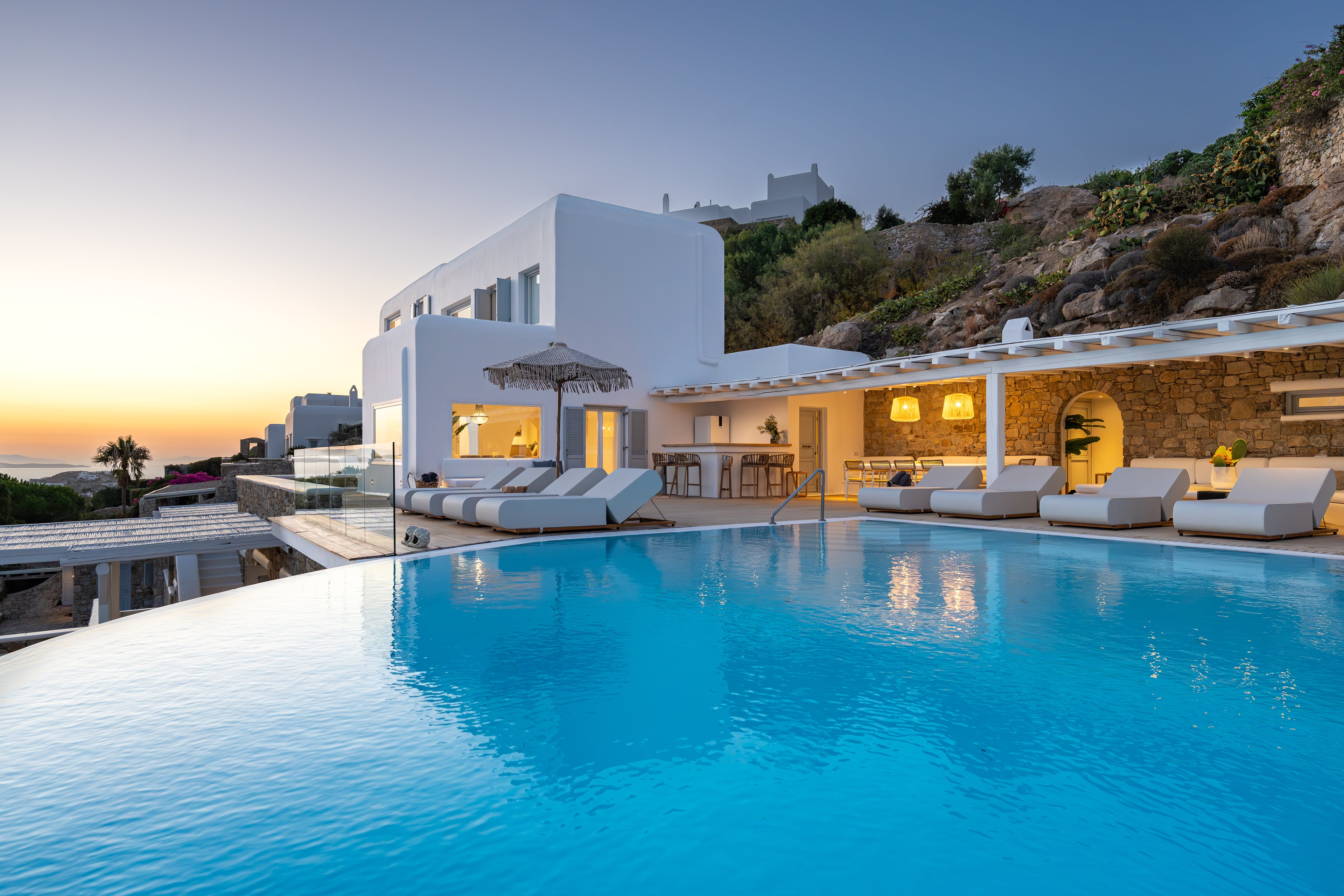 Luxury villa with pool and outdoor seating area at sunset.