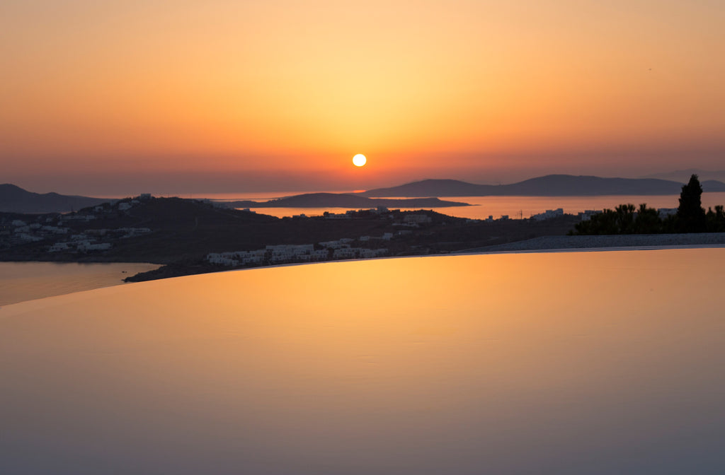 Sunset over a coastal landscape with a pool in the foreground