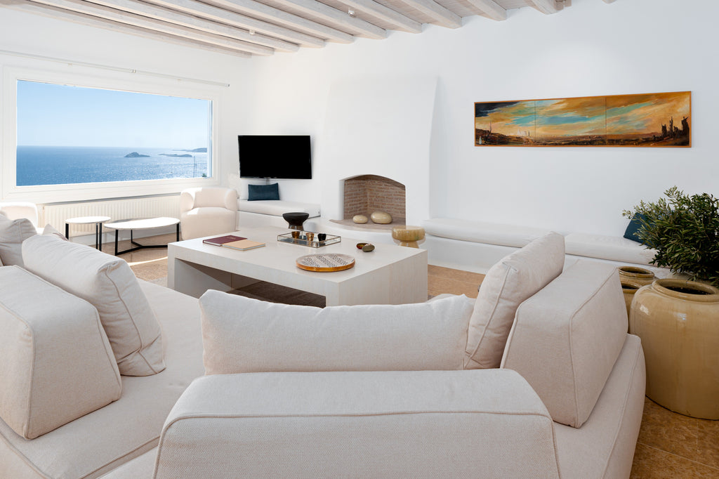 Modern living room with white furniture, ocean view, and decorative elements.