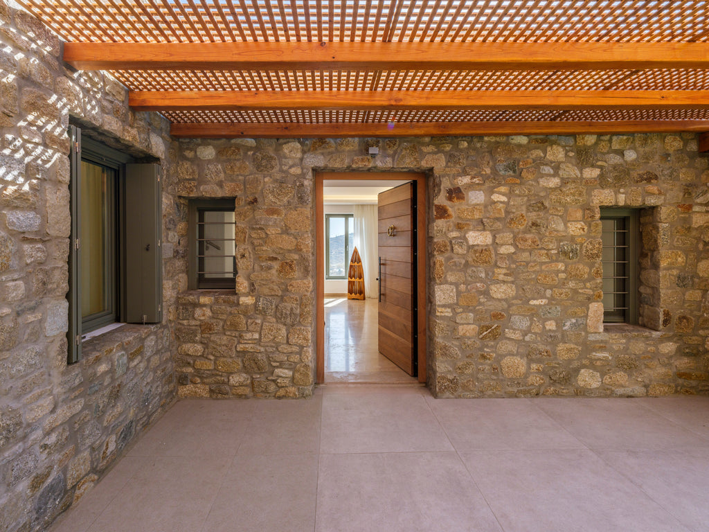 Stone-walled room with a wooden ceiling and open door leading to another room.