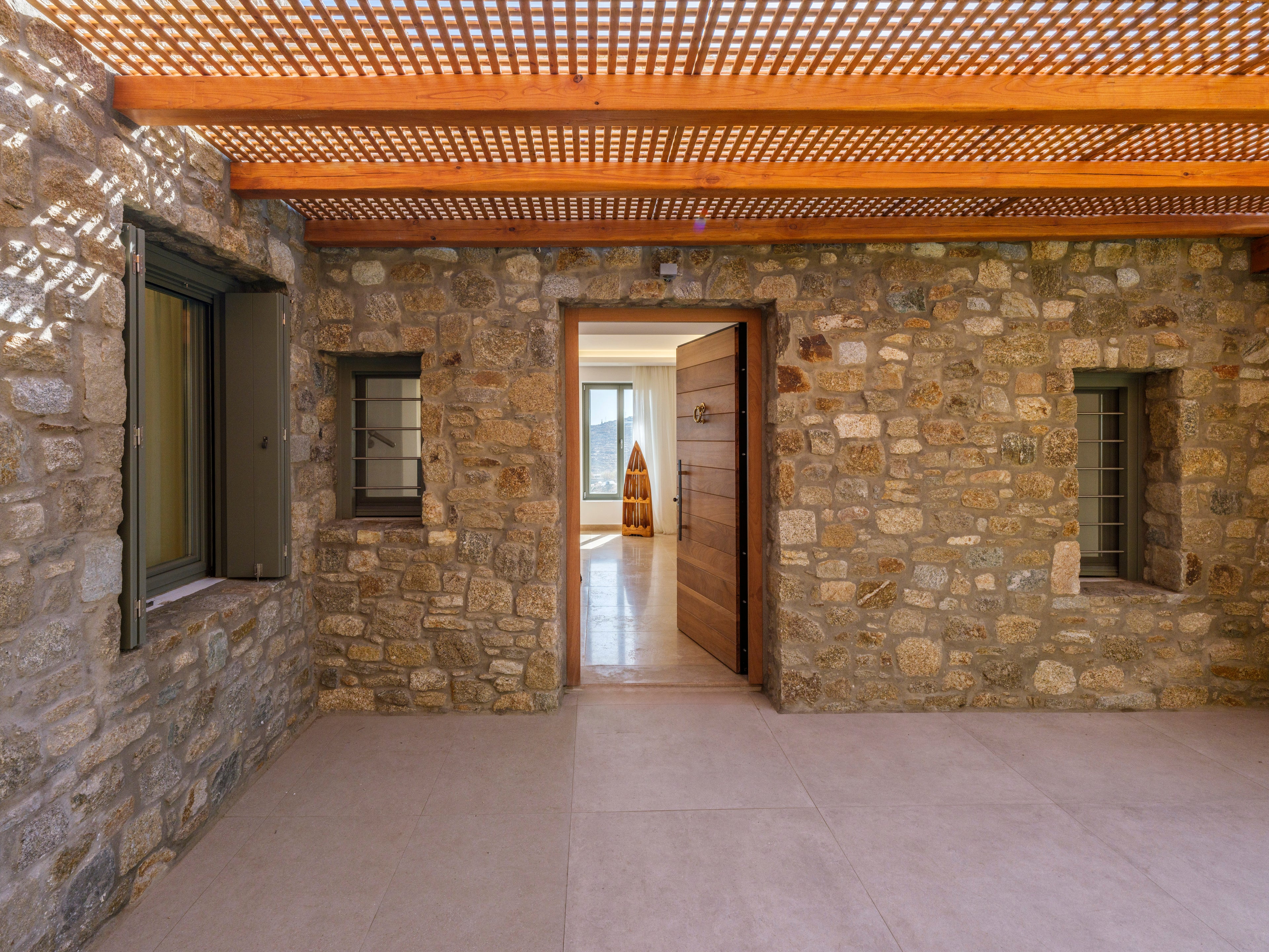 Stone-walled room with a wooden ceiling and open door leading to another room.
