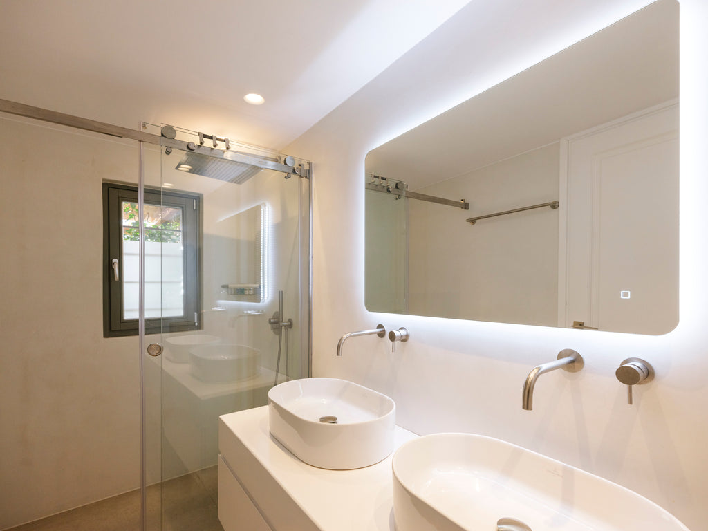 Modern bathroom with white vanity, sink, and mirror with LED lighting.
