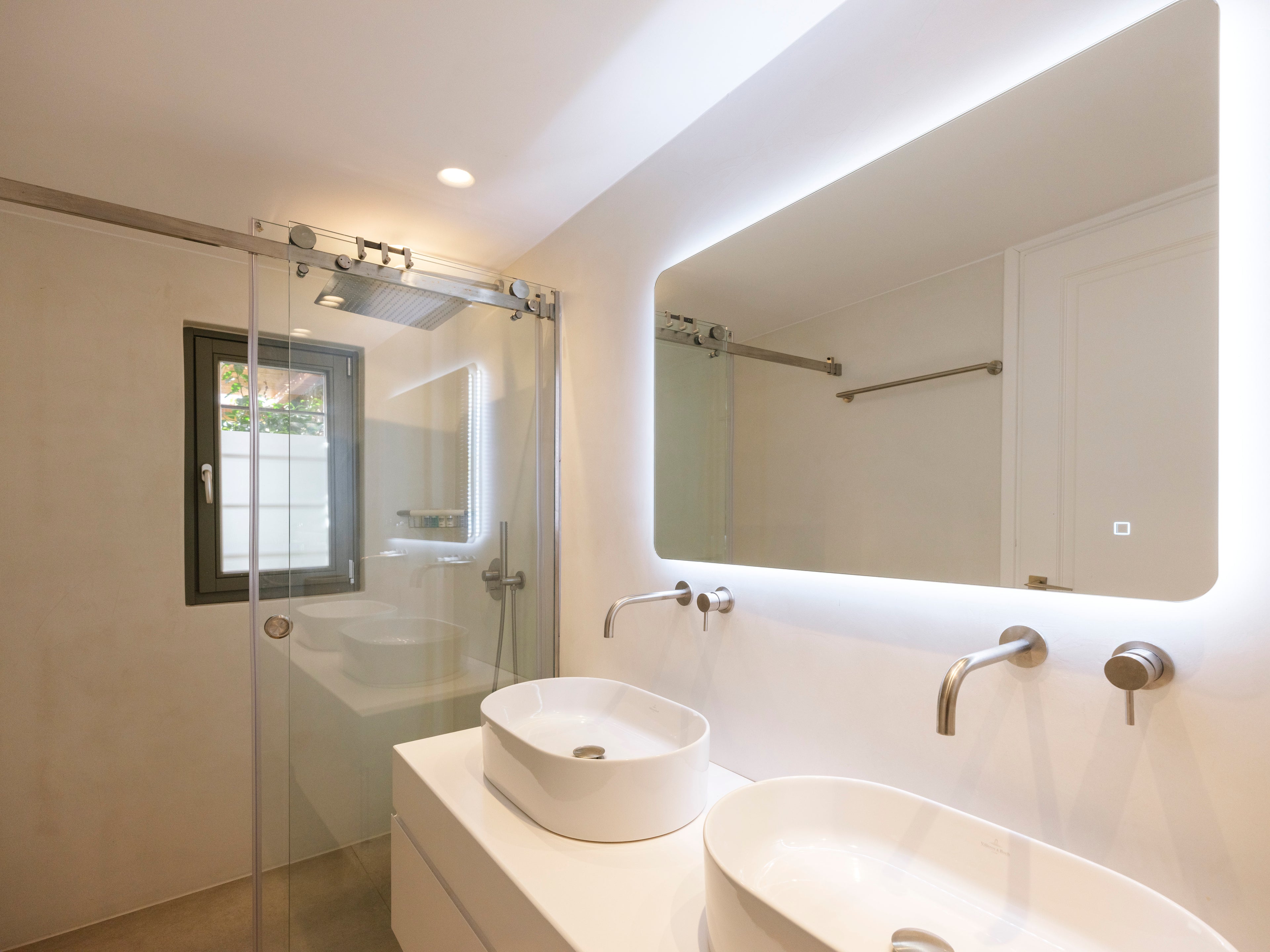 Modern bathroom with white vanity, sink, and mirror with LED lighting.