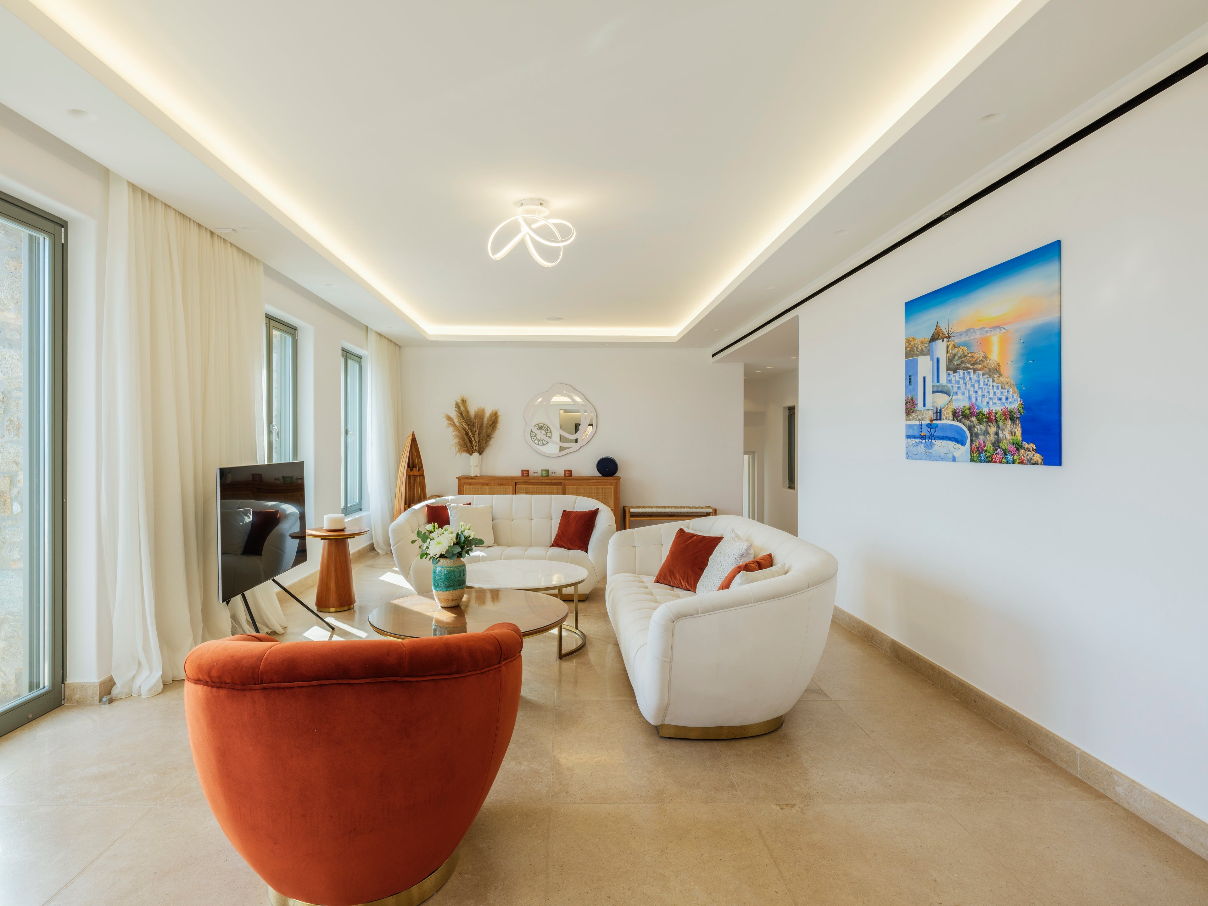Modern living room with white sofas, orange armchair, and a painting on the wall.