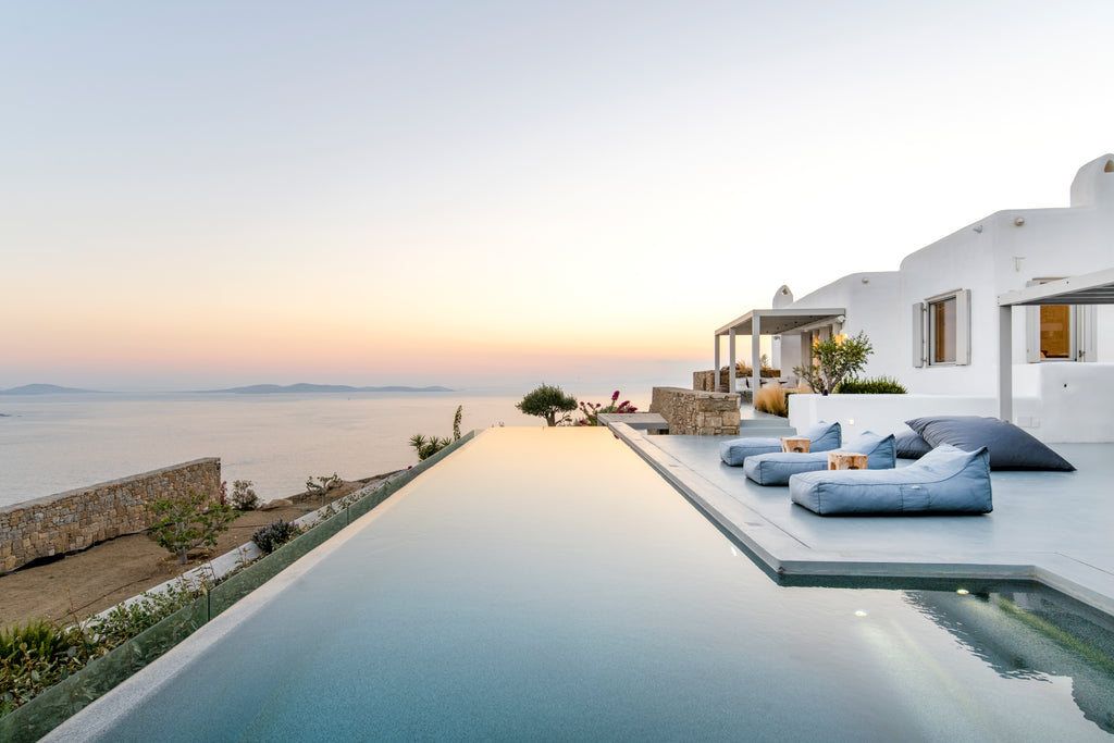 Luxury villa with infinity pool and outdoor seating area overlooking the sea.