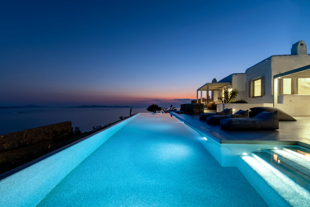Luxury villa with an infinity pool overlooking the ocean at dusk.