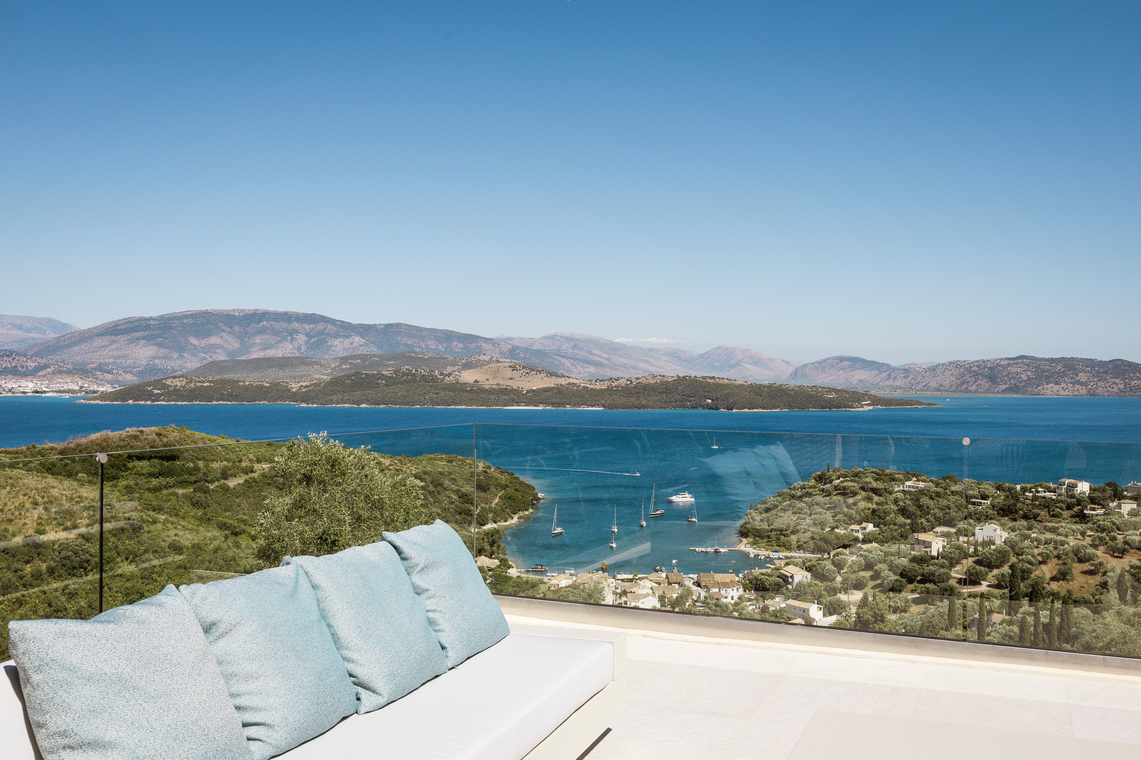 Outdoor seating area with a scenic view of a bay and mountains.