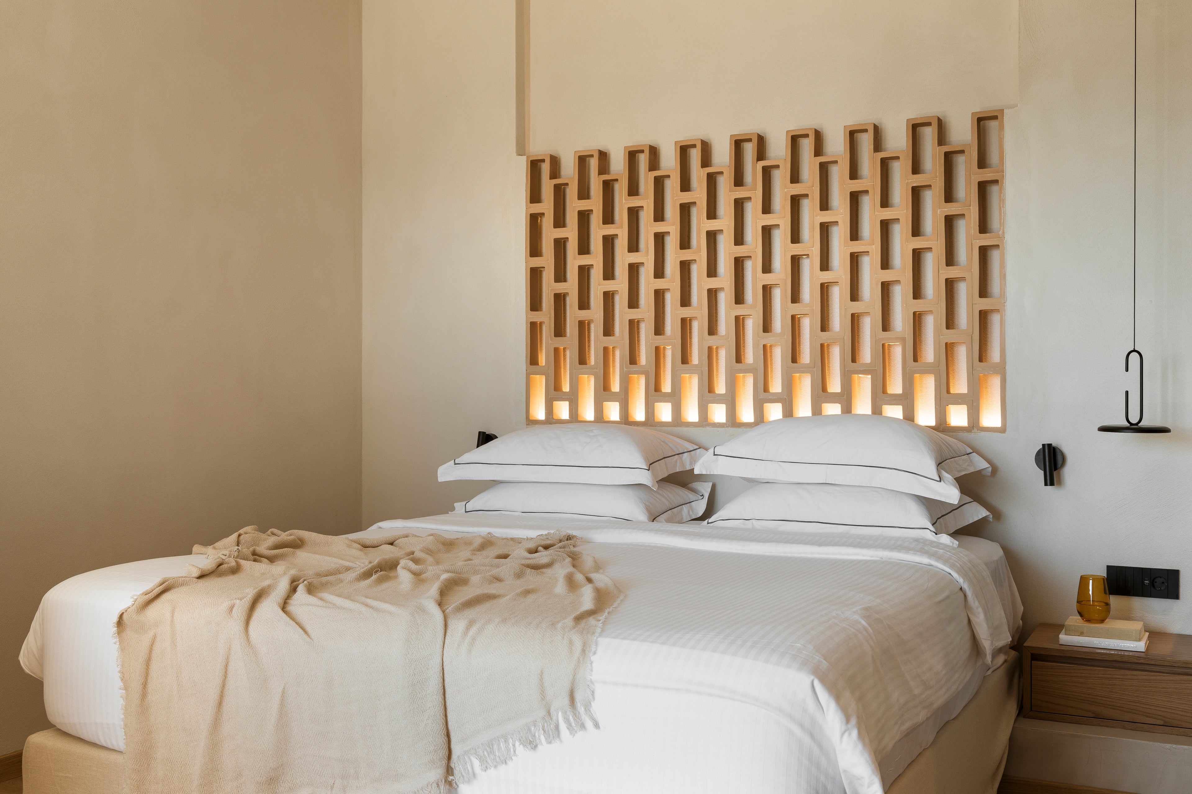 Bedroom with a decorative wooden headboard and soft lighting.