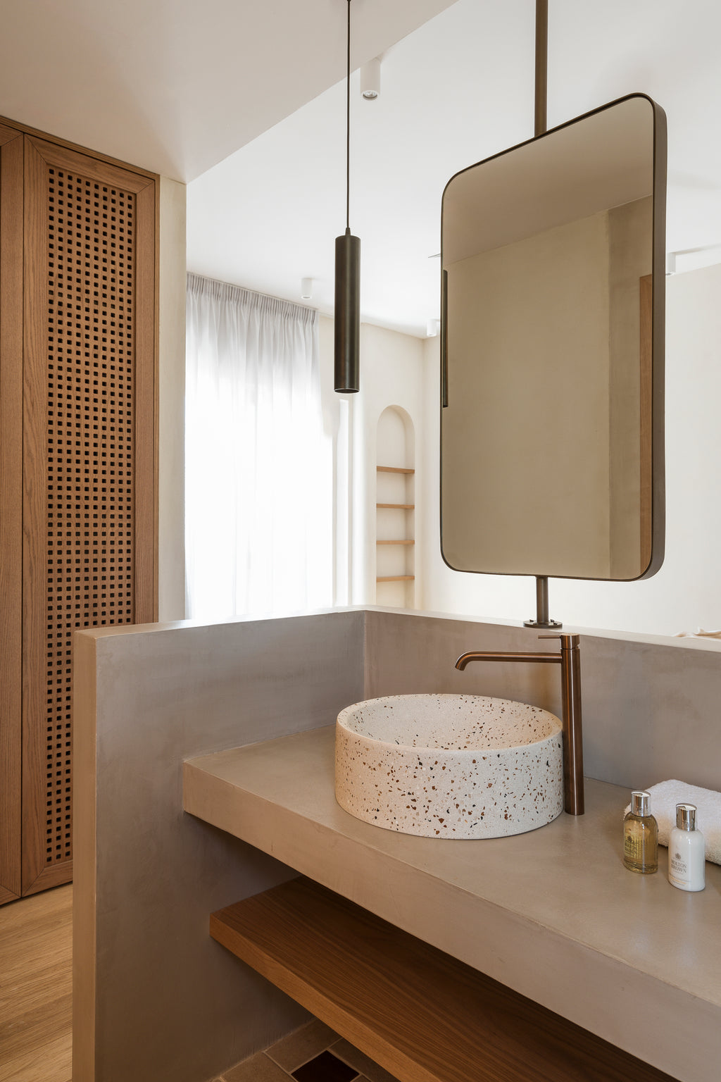 Modern bathroom vanity with speckled sink, mirror, and lighting fixture.