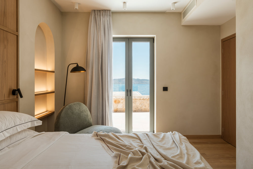 Modern bedroom with a bed, lamp, and large window with curtains.