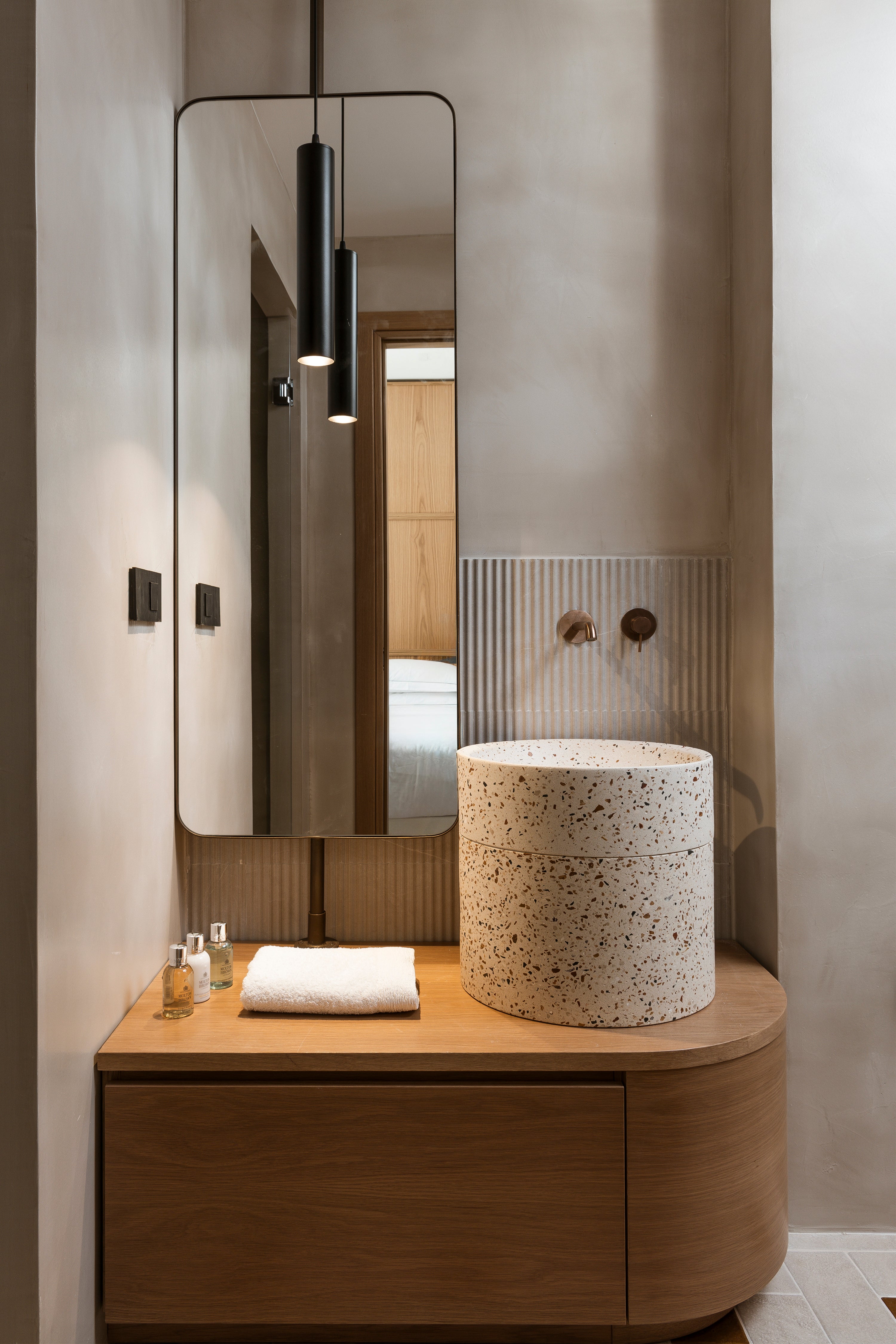Modern bathroom with wooden vanity, speckled countertop, and large mirror.