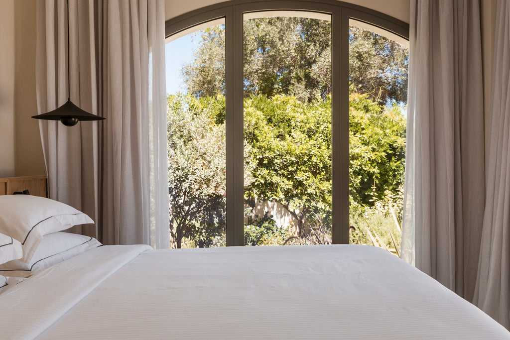 Bedroom with a large window showing greenery outside