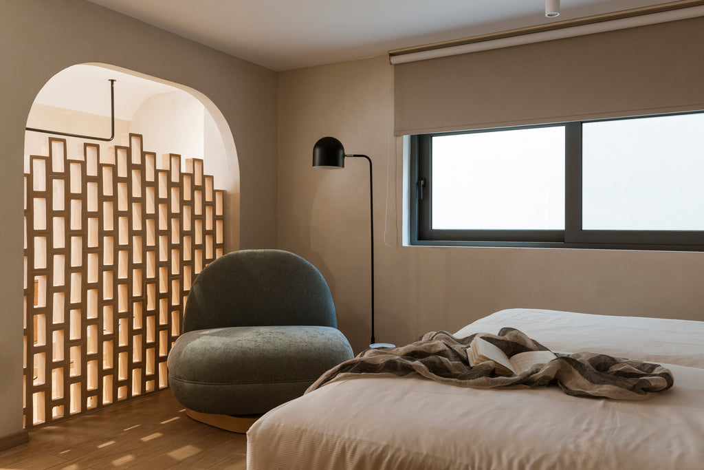 Modern bedroom with a textured wall, chair, and bed.