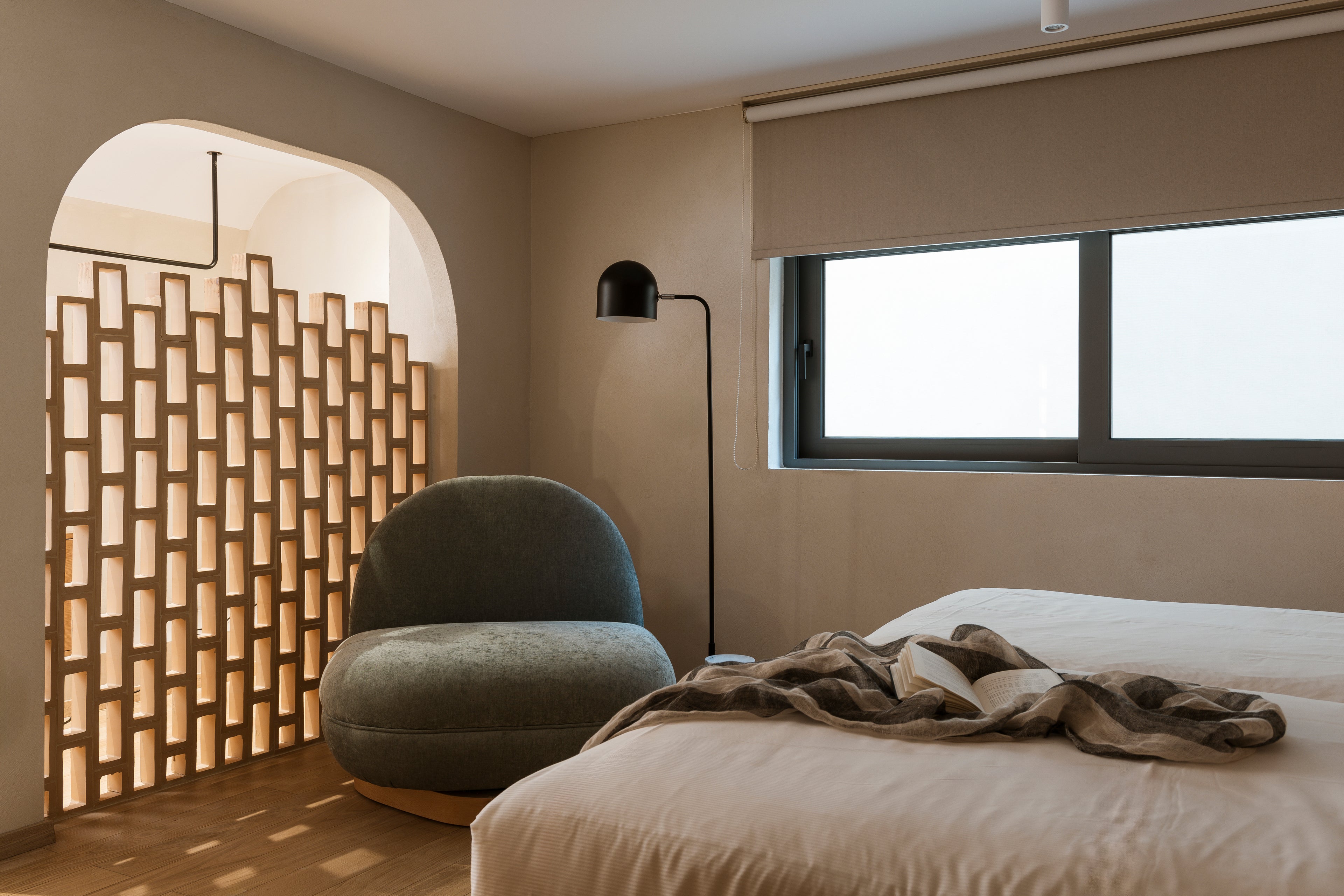 Modern bedroom with a textured wall, chair, and bed.