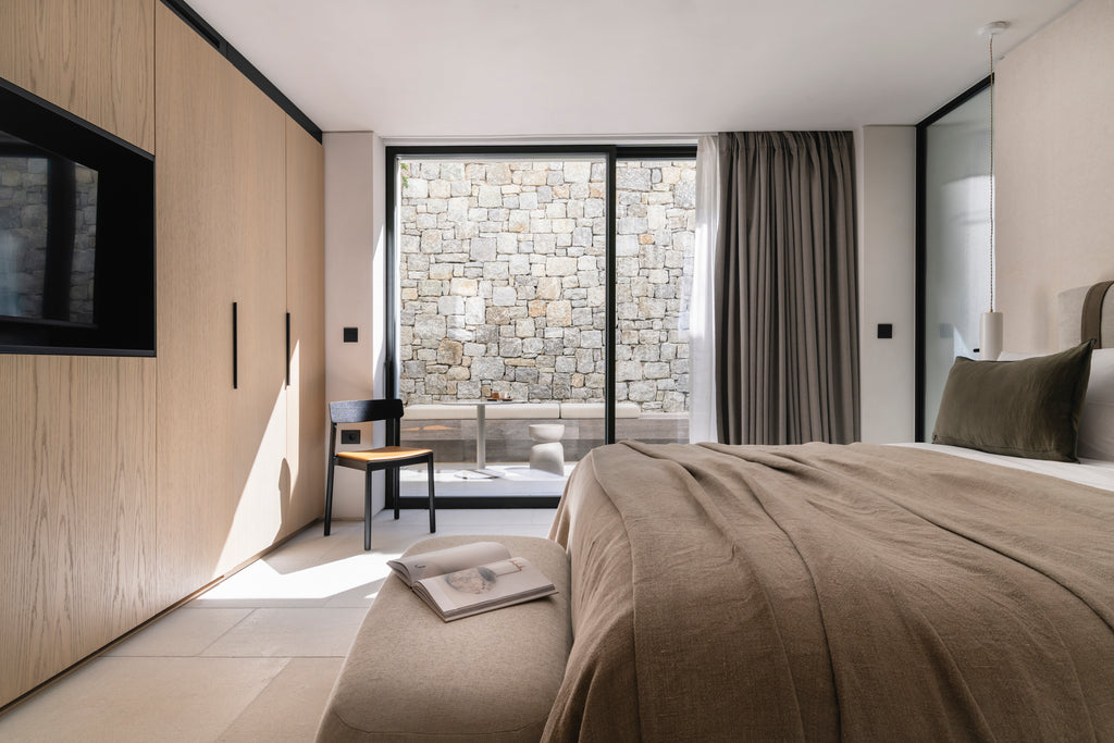 Modern bedroom with bed, TV, and stone wall view