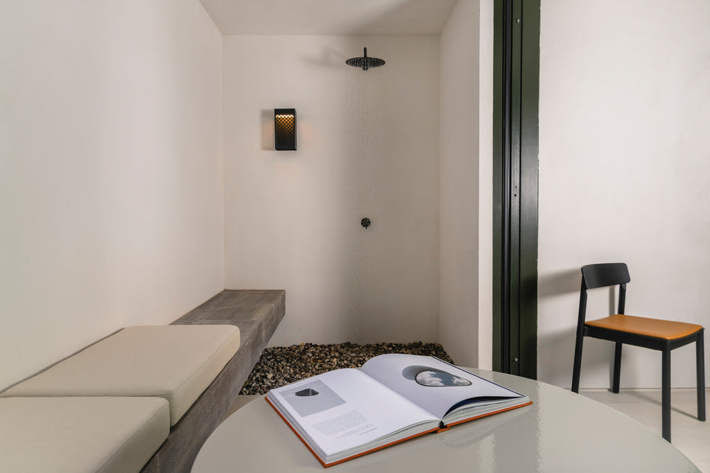 Minimalist room with an open book on a table, a chair, and a small bench.
