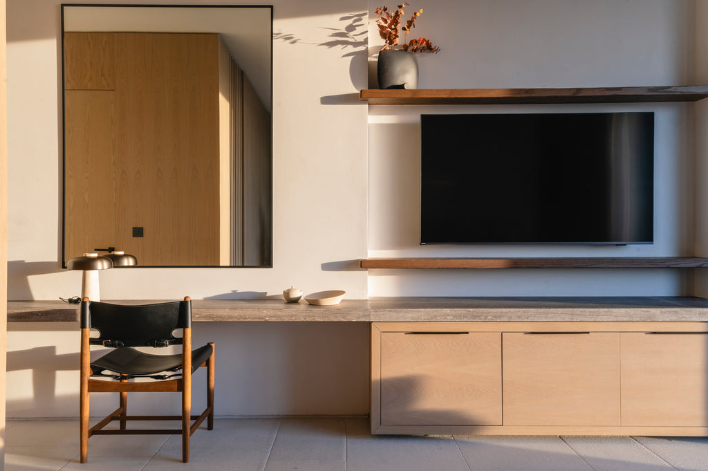 Modern bedroom with a TV mounted on a wall, wooden cabinet, and chair.