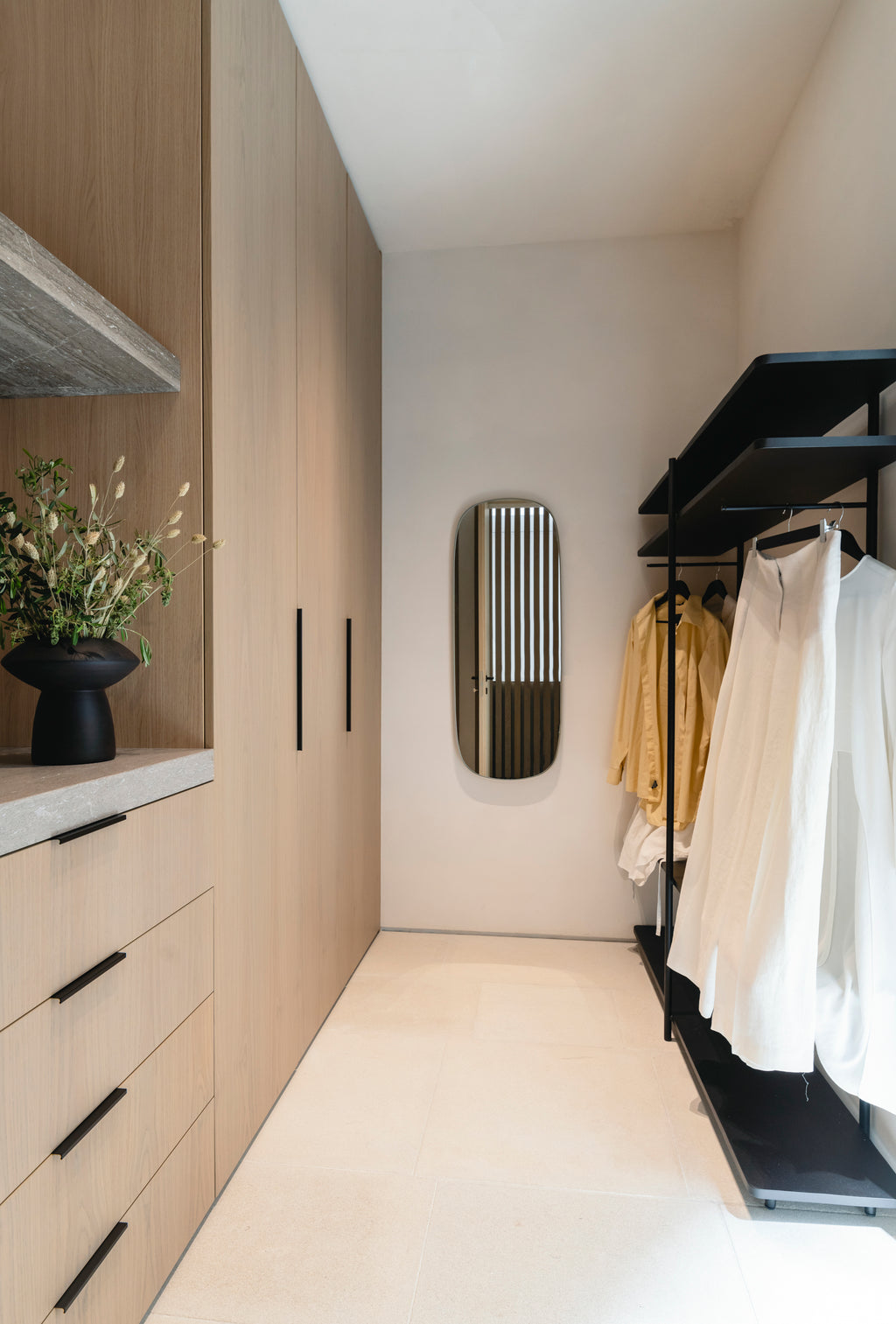 Modern walk-in closet with wooden wardrobe, clothing rack, and decorative elements.