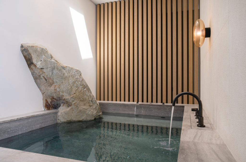 Indoor hot tub with a stone wall and wooden paneling in a modern setting
