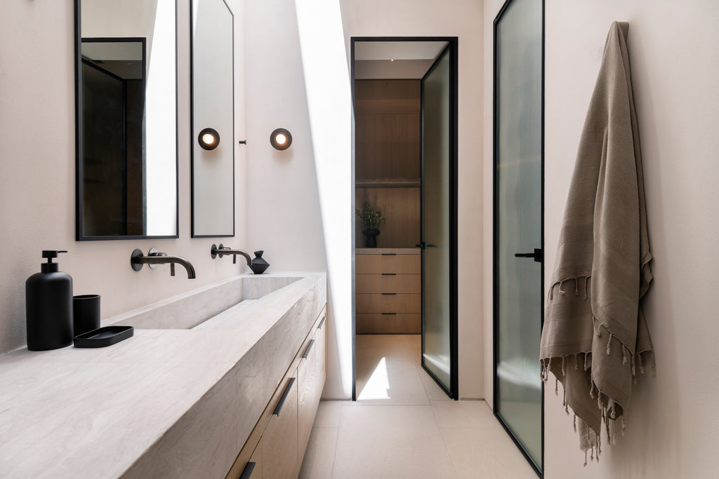 Modern bathroom with white vanity, mirrors, and a towel hanging on the wall.