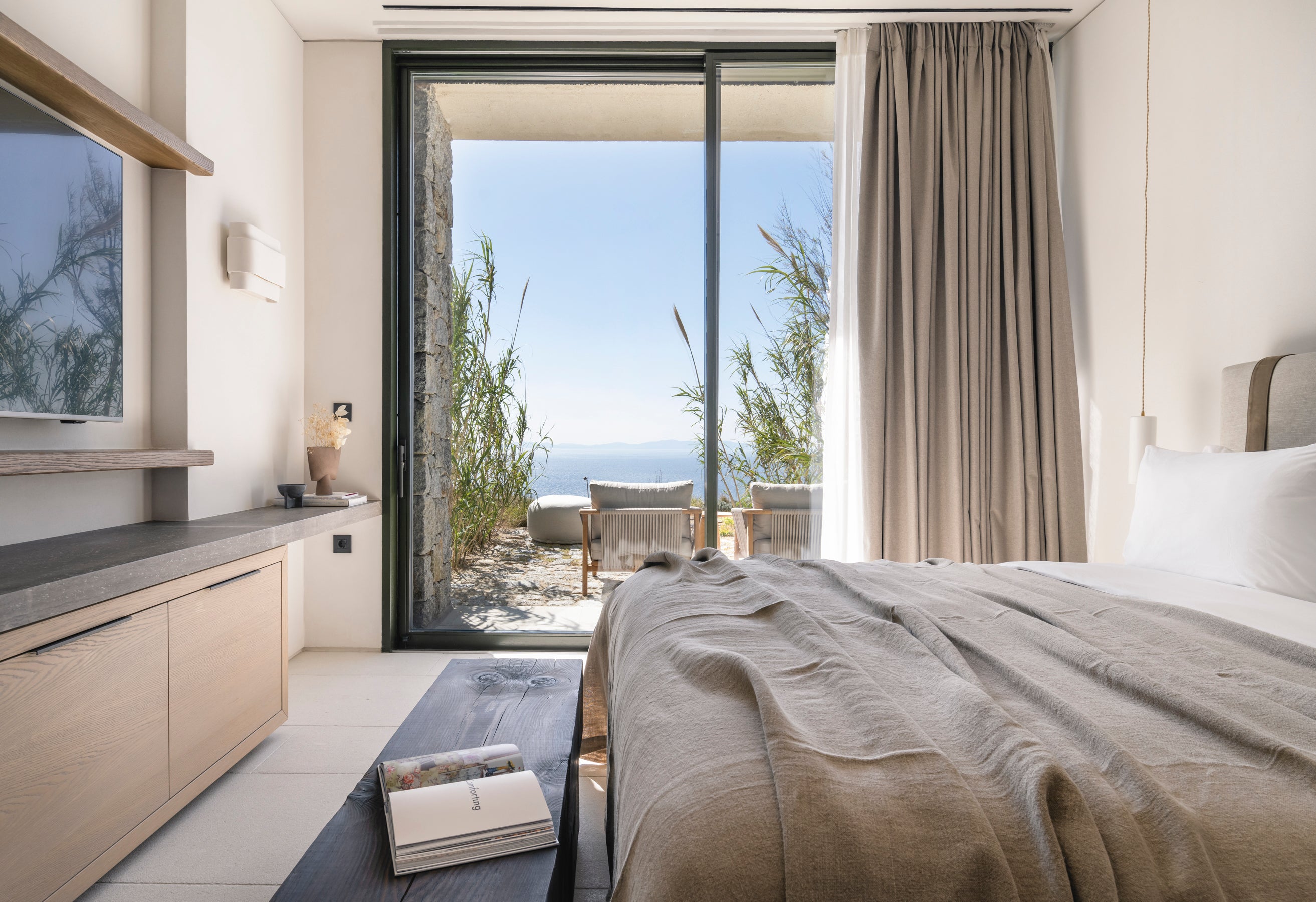 Modern bedroom with a view of the ocean through large windows.