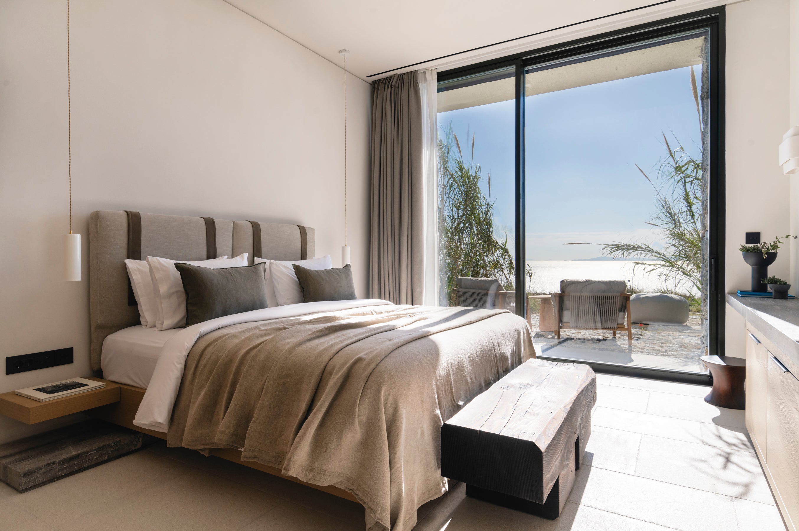 Modern bedroom with a large bed and sliding glass door leading to an outdoor area.