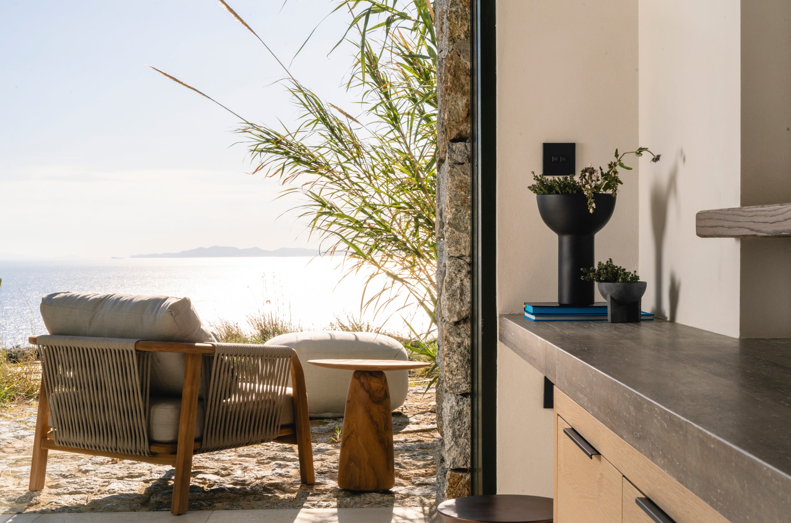 Outdoor seating area with a view of the ocean and a modern interior.
