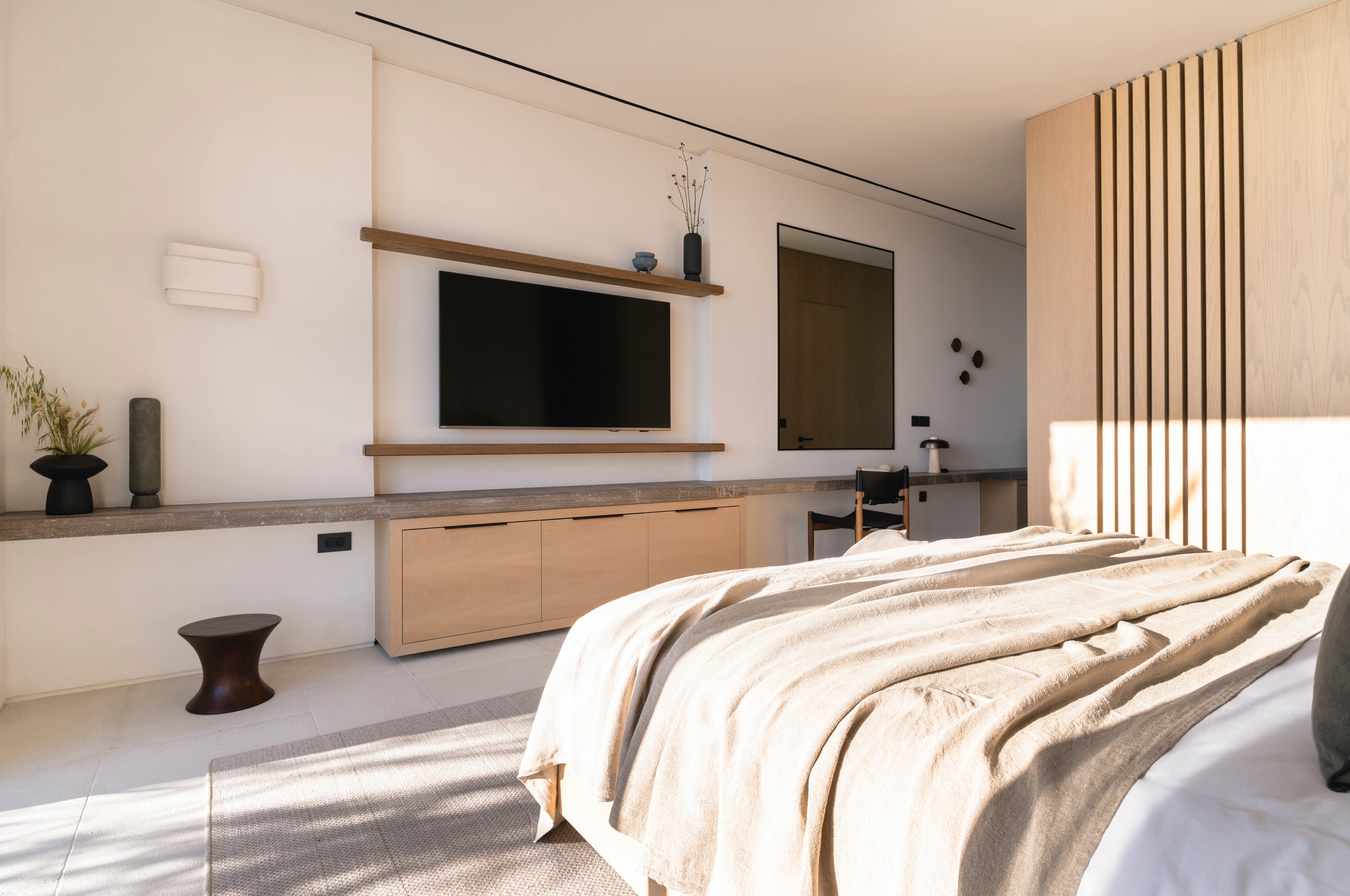 Modern bedroom with a bed, television, and minimal decor.