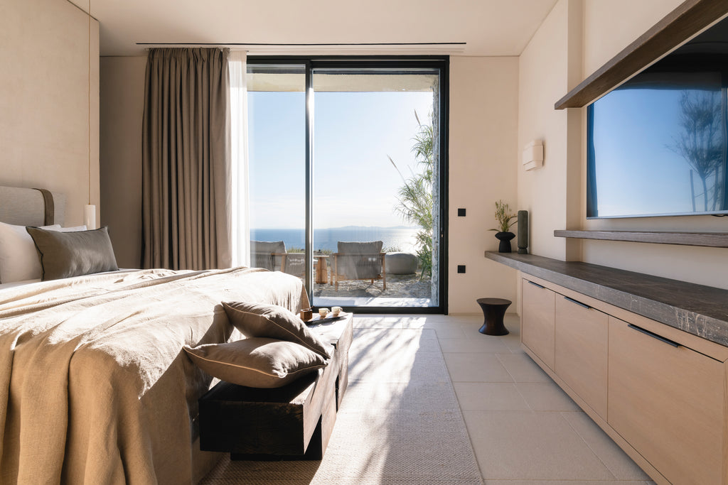 Modern bedroom with a large bed, sliding glass door, and ocean view.