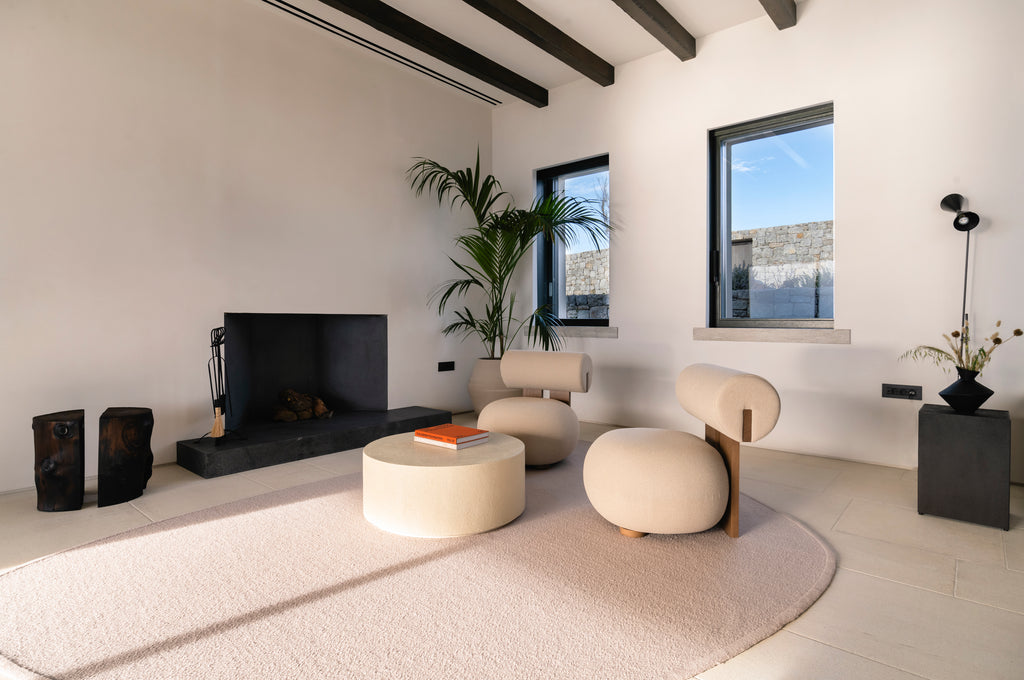 Modern living room with a fireplace, white furniture, and large windows.