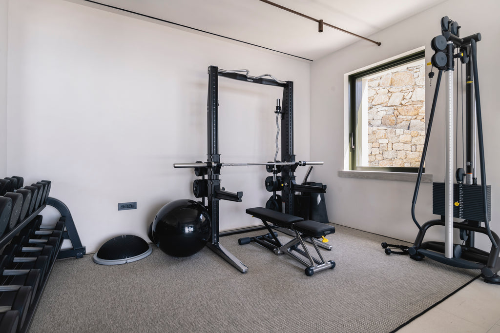 Home gym with weightlifting equipment in a room with a stone wall.