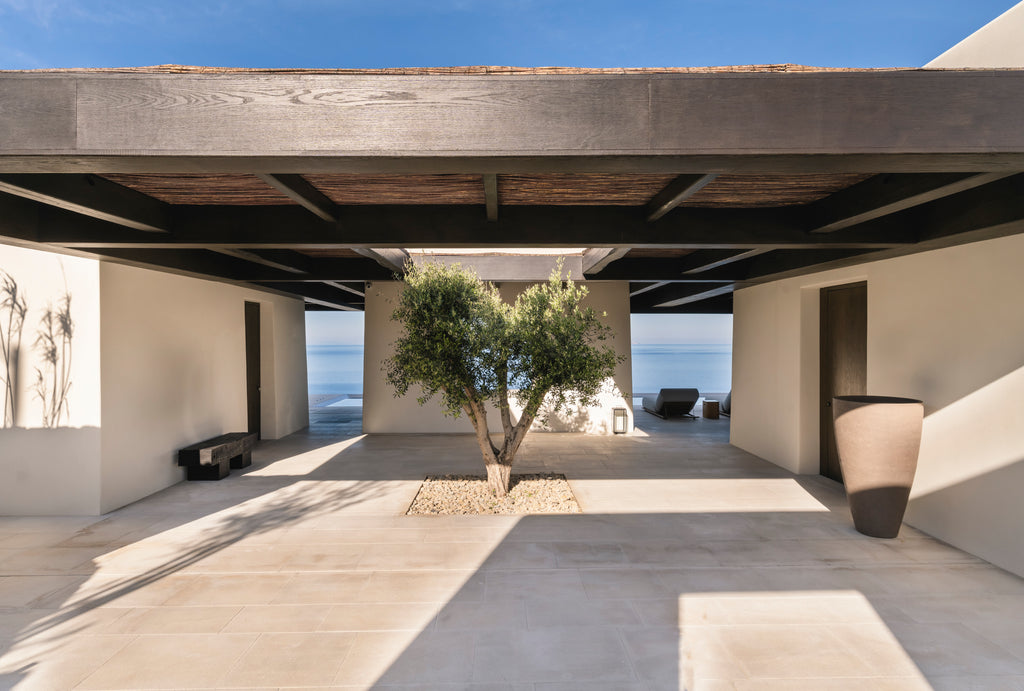 Modern outdoor patio with ocean view, concrete floor, and minimalistic design.