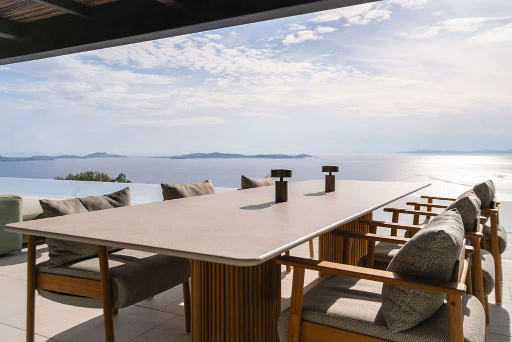 Outdoor dining table with chairs by a scenic waterfront